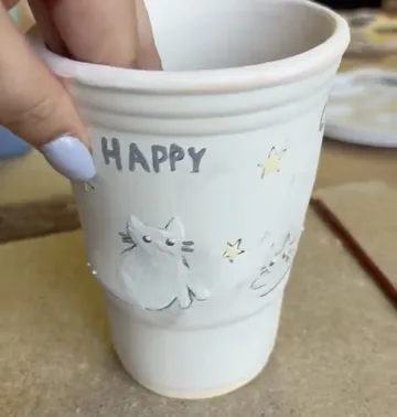 Tasse mit gemaltem Cartoon-Katze gehalten.