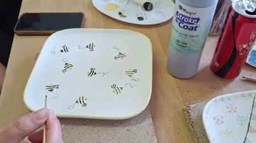 Hand painting bees on ceramic plate.