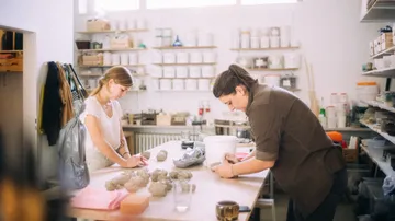 Zwei Frauen formen Keramik im Studio.
