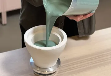 Hands pour liquid into ceramic mold.