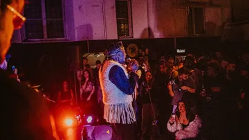 Singer performing on stage with audience watching.