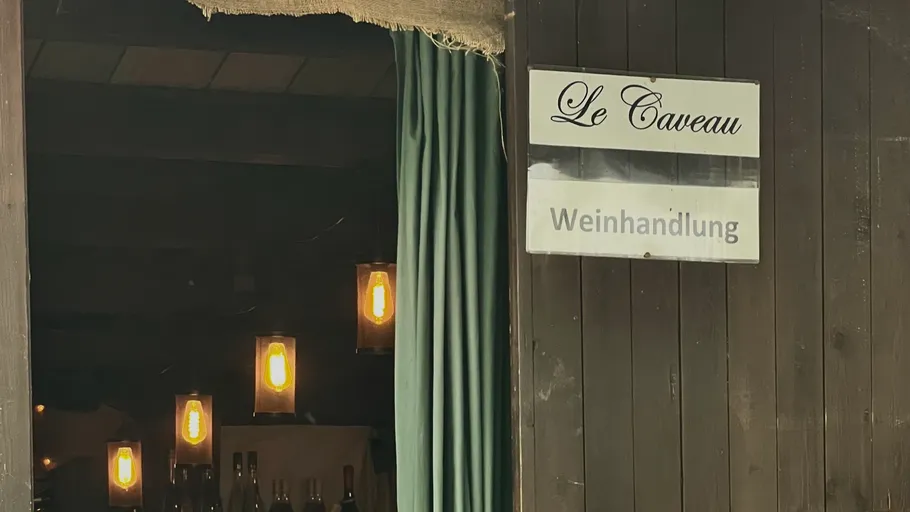 Weinladen-Eingang mit beleuchteten Hängelampen.