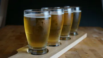 Four beer glasses on wooden tray.