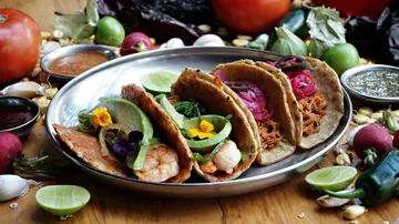 Drei verschiedene Tacos auf silbernem Teller.