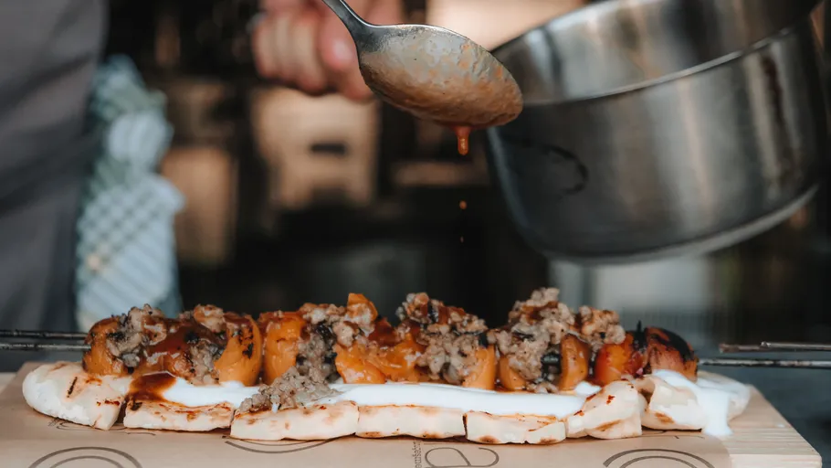 Person pours sauce over a bread dish.