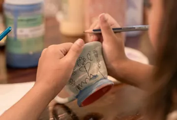 Person bemalt Keramiktasse mit Design.