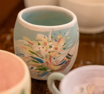 Bunt bemalter Becher mit Blumenmuster.