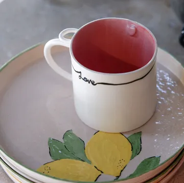 Tasse mit 'Love'-Text auf Zitronen-Teller.
