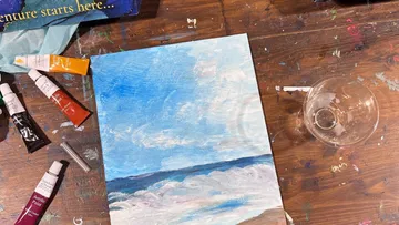 Gemälde und Kunstmaterialien auf Holztisch.