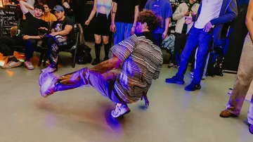 Tänzer führt Breakdance auf, Zuschauer schauen zu.
