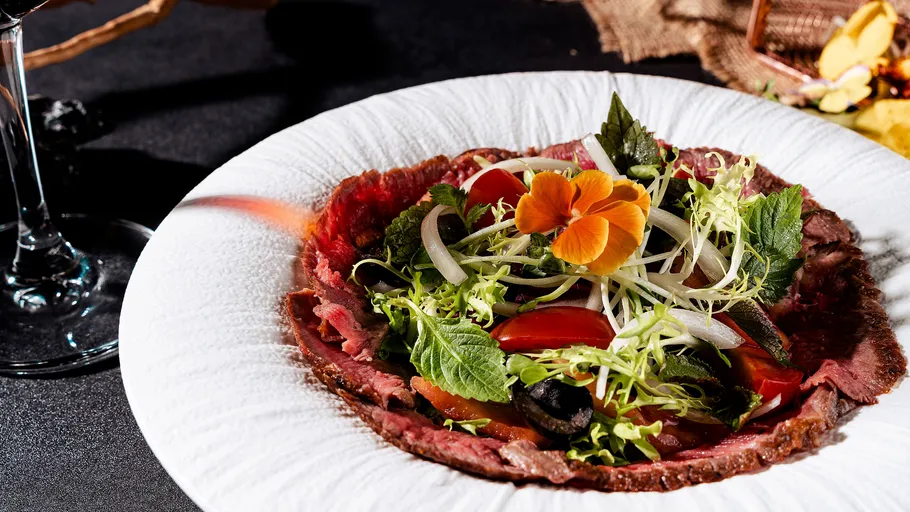 Teller mit Carpaccio und Salatbeilage.
