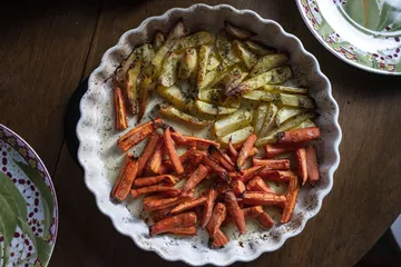 Carrots and potatoes roasted in white dish.