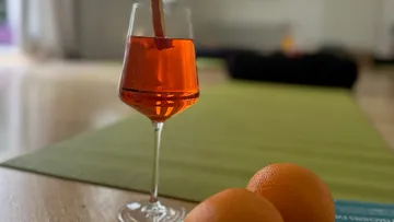 Glas mit orangefarbenem Getränk auf Yogamatte.