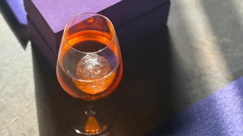 Weinglas mit orangefarbenem Getränk auf Tisch.