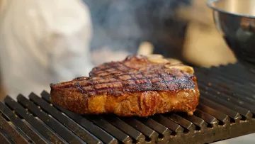 Steak brutzelt auf dem Grill, Küchenhintergrund.