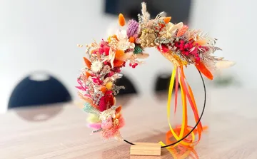 Floral crown displayed on wooden stand, table background.