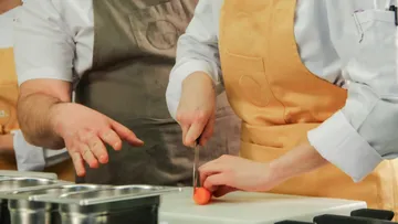 Koch schneidet Karotte in Küchenumgebung.