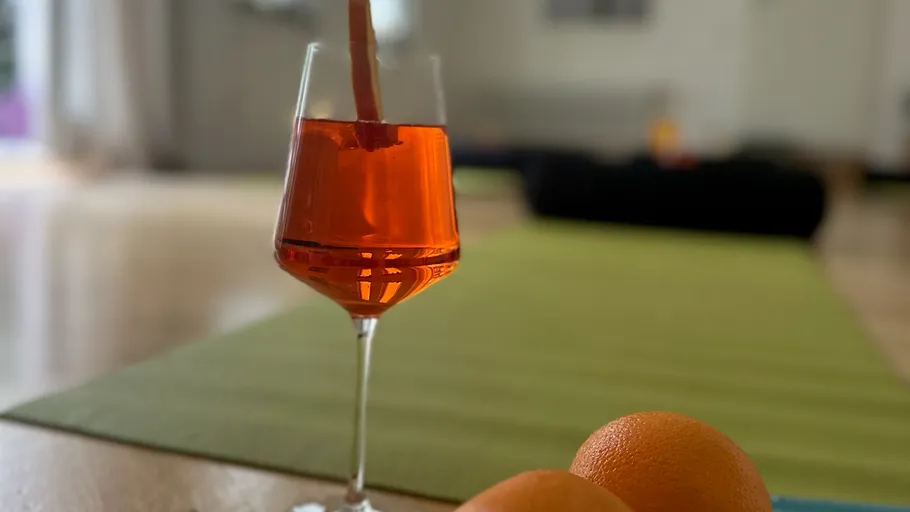 Glass of orange drink indoors with oranges.