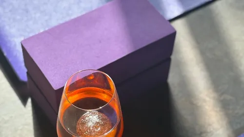 Glas mit orangener Flüssigkeit auf Tisch.