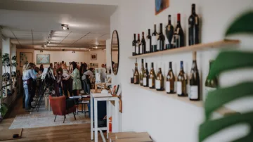 Wine bottles on shelf, people painting workshop.