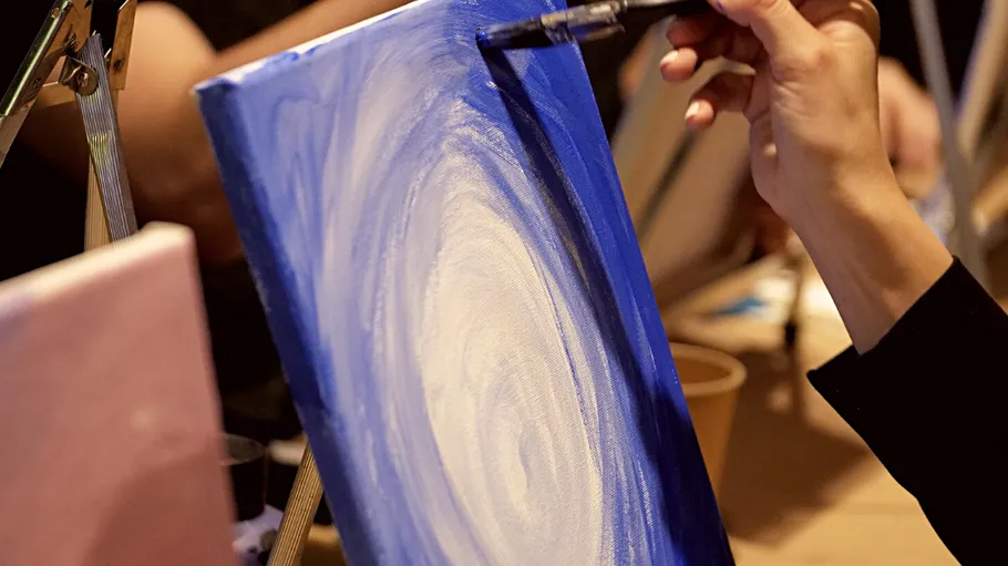 Hand painting blue and white canvas indoors.