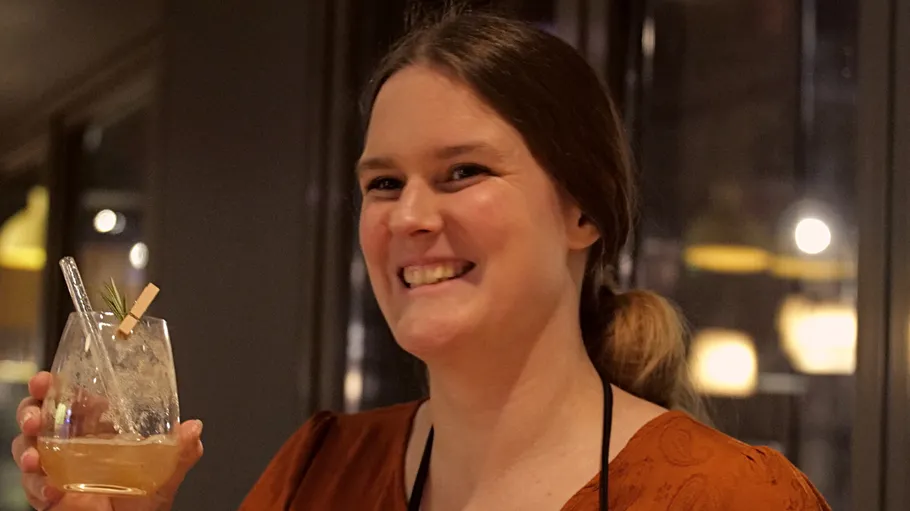 Woman holding drink, smiling indoors.