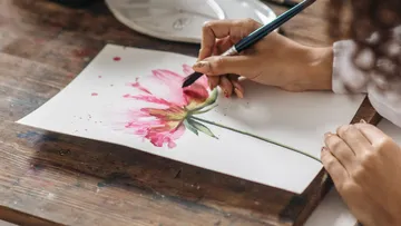 Hand painting flower on paper, wooden table.