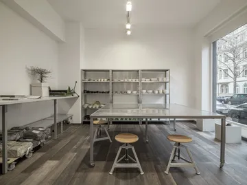 Studio-Arbeitsplatz mit Tischen und Regalen.