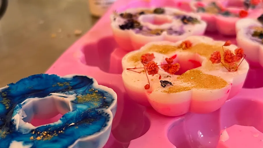 Bunte Wachsschmelzen in Blumenformform.