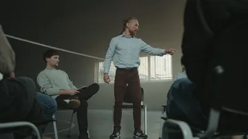 Man leading group discussion in dim room.