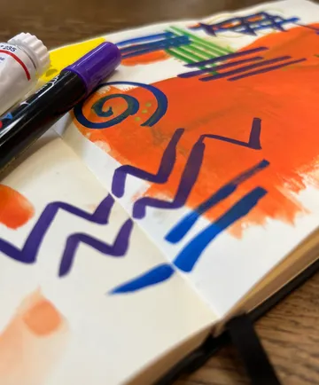 Colorful markers drawing on open notebook.