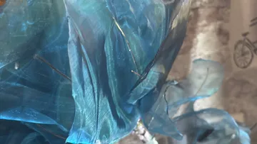 Blauer transparenter Stoff mit Draht im Sonnenlicht.