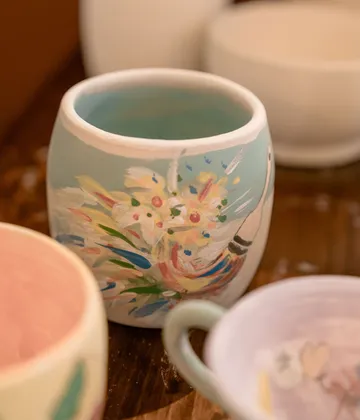 Bemalter Keramikbecher mit abstraktem Blumendesign.