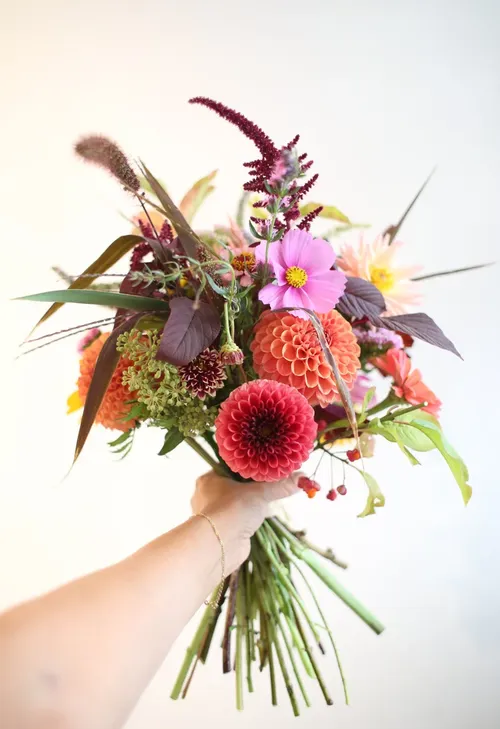 Hand holding colorful flower bouquet.