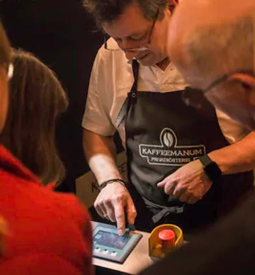 Man operates a device to prepare coffee in a busy environment.