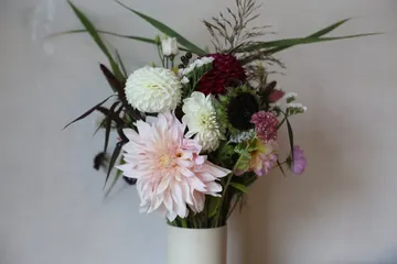 Blumenstrauß mit verschiedenen Blumen in weißer Vase.