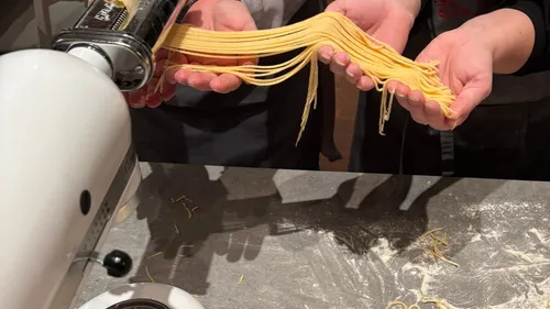 Hände halten frische Pasta aus Maschine.