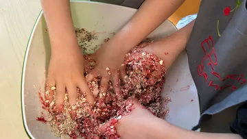 Hände mischen Müsli in einer Schüssel.