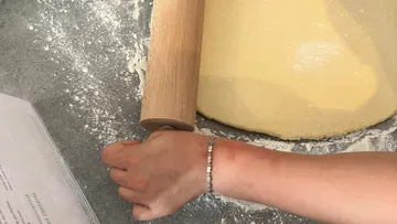 Hand rolling dough on floured surface.