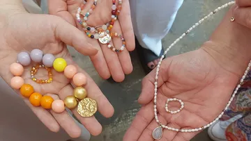 Hands displaying different colorful bead jewelry.