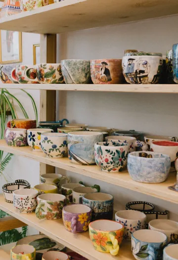 Colorful mugs arranged on wooden shelves.