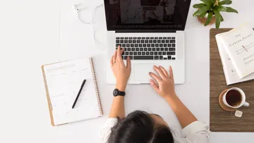Person tippt auf Laptop am Schreibtisch.