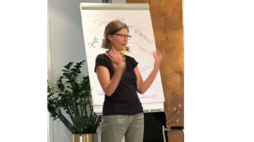 Frau spricht vor einem Flipchart.
