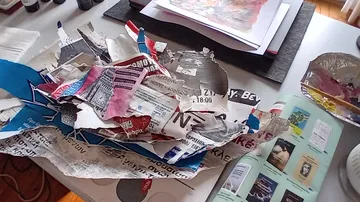 Zerrissene Papierschnipsel auf chaotischem Schreibtisch.