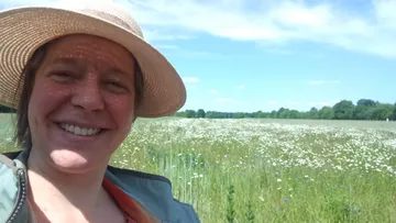 Marion Thishen-Hendess lächelt auf Wiese mit Wildblumen.