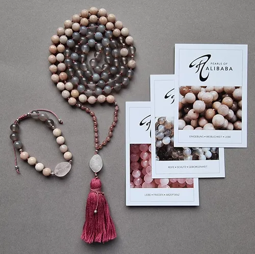 Beaded necklace and bracelet on grey surface.