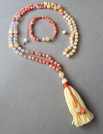 Perlenkette und Armband auf grauer Oberfläche.