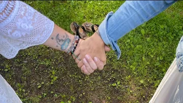 Zwei Personen halten Hände auf Gras.