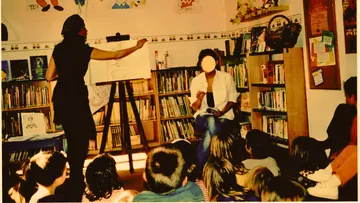 Frau unterrichtet Kinder in einer Bibliothek.
