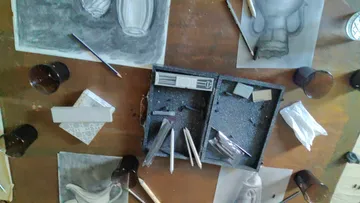 Kunstbedarf liegt auf Holztisch.